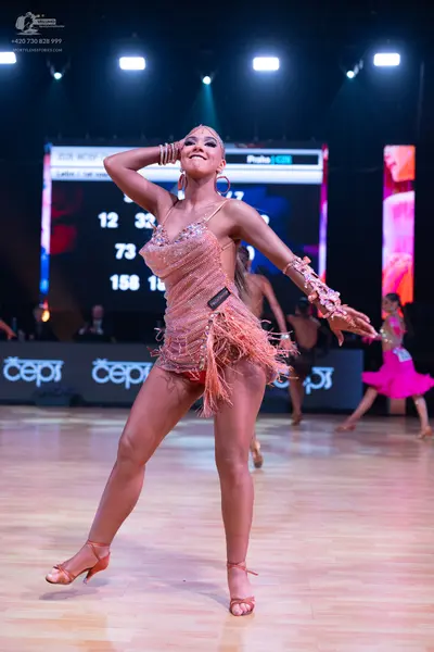 Dancesport competitor: Female dancer in foreground: nude-colored sequined Latin dance dress with long f