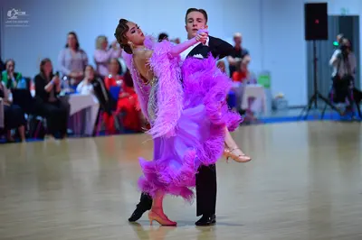 Dancesport competitor: Female dancer: voluminous pink/magenta dance dress with many layers of feathers 