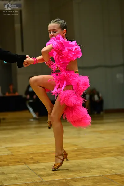 Dancesport competitor: Female dancer: bright pink Latin dance costume with many ruffled or textured lay