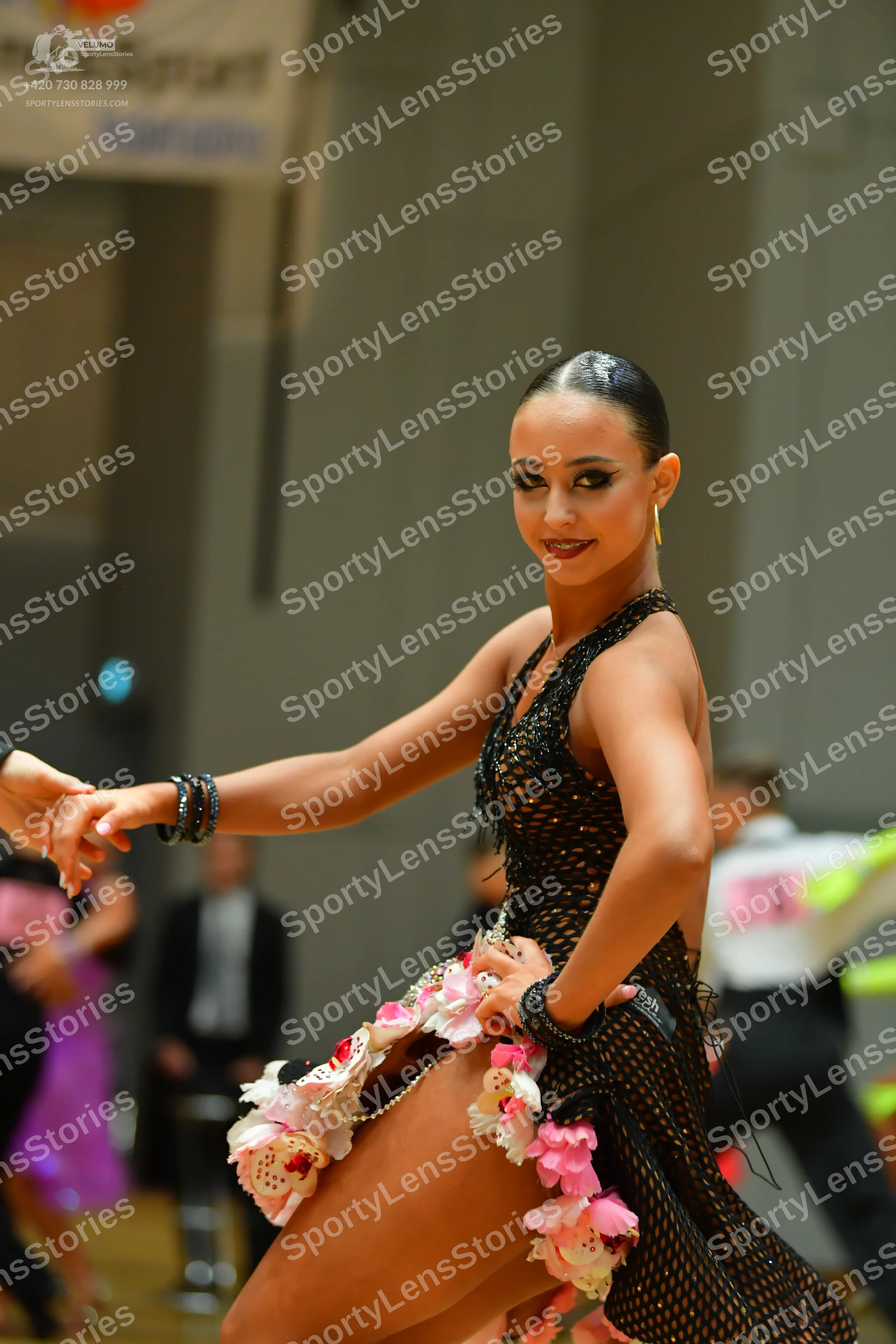 Dancesport competitor: Female dancer: black sleeveless Latin dress featuring a net/mesh fabric with seq