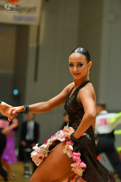 Dancesport competitor: Female dancer: black sleeveless Latin dress featuring a net/mesh fabric with seq