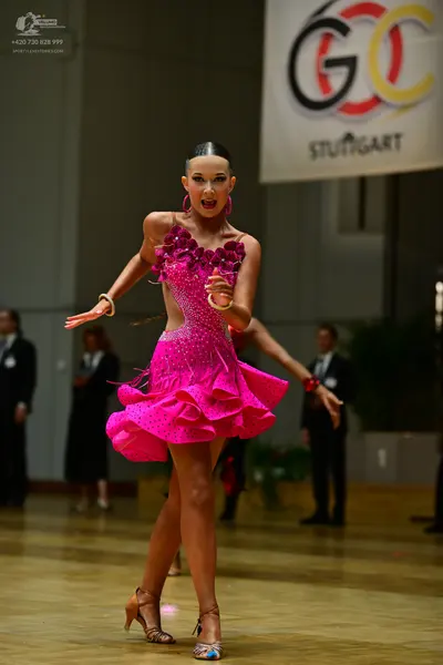 Dancesport competitor: Female dancer: bright pink Latin dance dress with sequins, featuring cutouts and