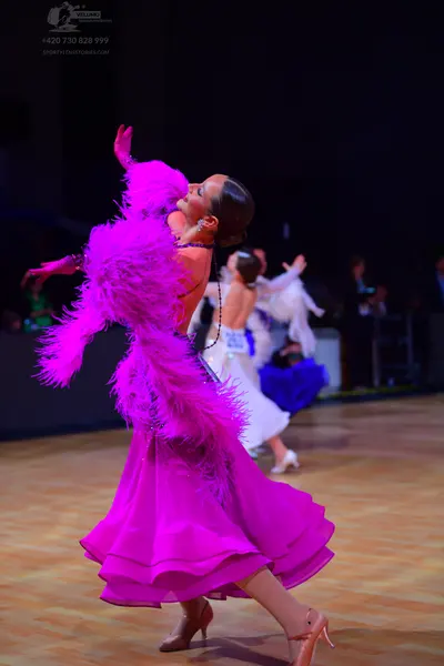 Dancesport competitor: Female dancer: bright pink long latin dress with large feather trim and a flowin