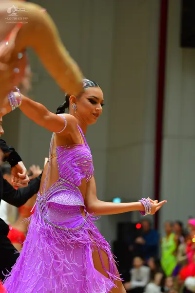 Dancesport competitor: Female dancer: purple Latin dress with a sequined bodice and long fringe skirt