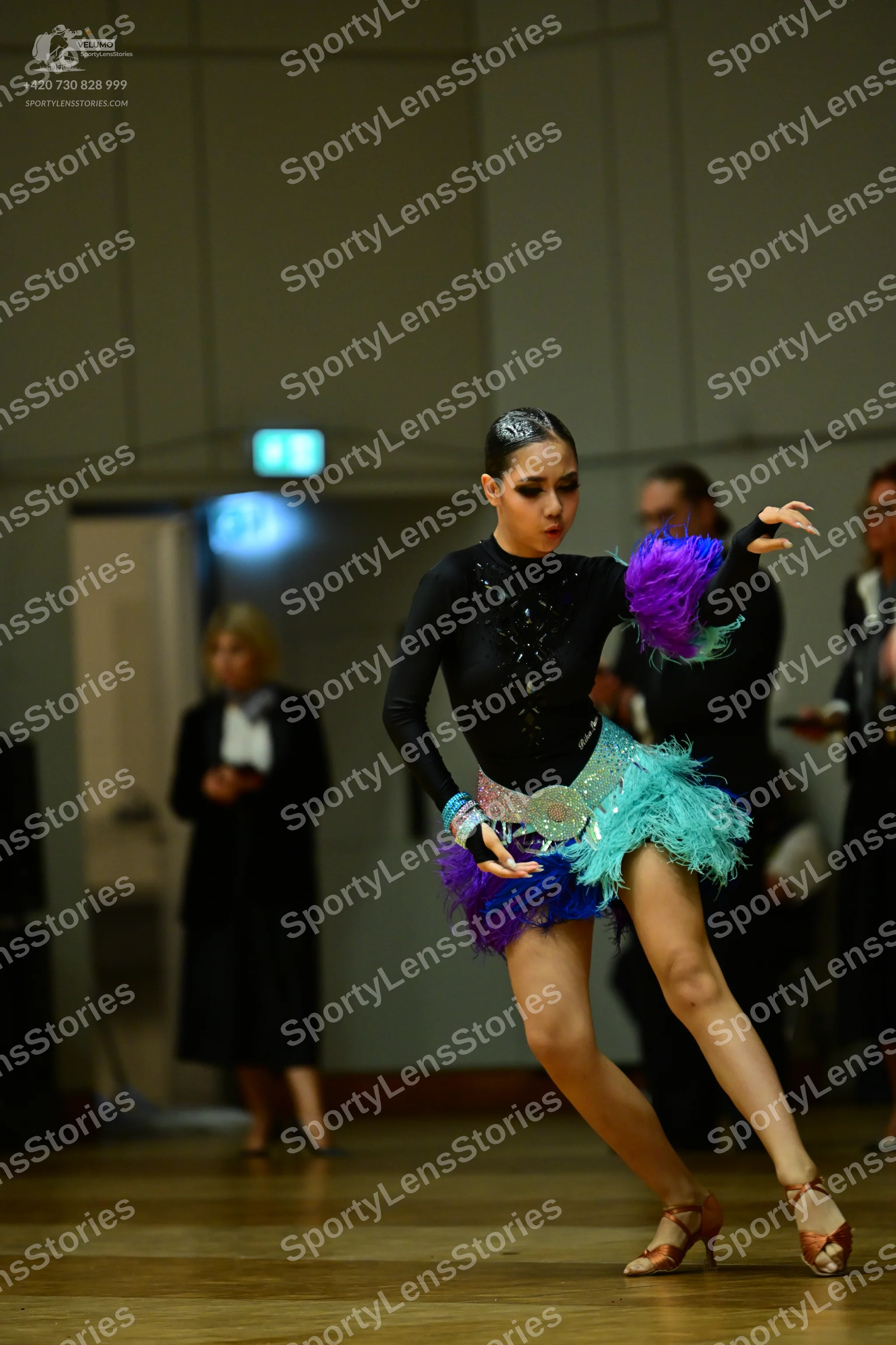 Dancesport competitor: Female dancer: black long-sleeved bodysuit with a multi-colored feathery skirt i