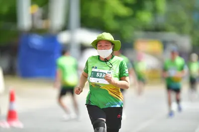 Marathon runner #533: Runner 1: green and yellow patterned jersey, black shorts, green sun hat, white 