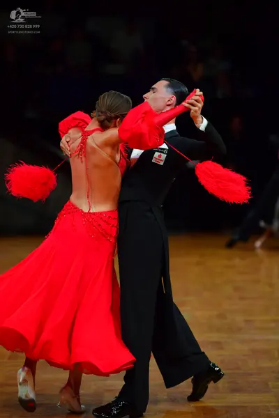 Dancesport competitor: Female dancer: red ballroom dress with a low back, featuring large red fluffy or