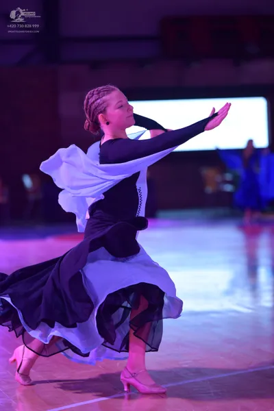 Dancesport competitor: Female dancer in foreground: black long-sleeved bodice with a voluminous, multi-