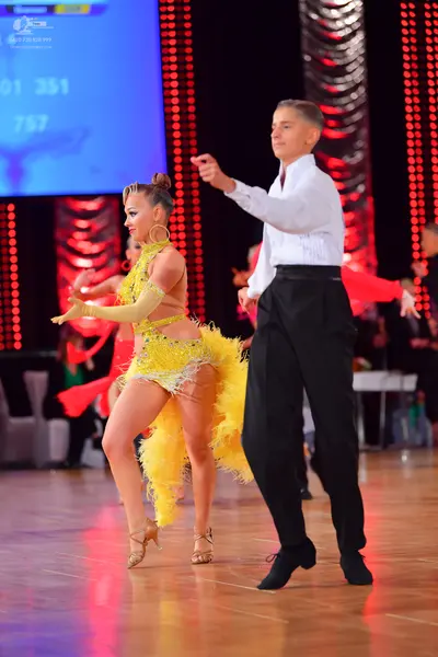 Dancesport competitor: Female dancer: yellow latin dress with fringe and sheer details, matching yellow