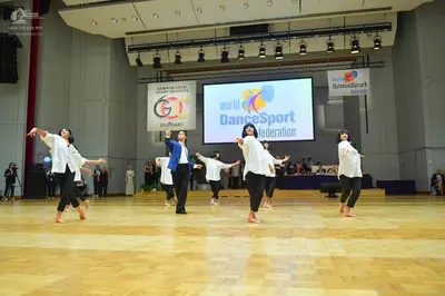 Dancesport competitor: All dancers: white long-sleeved tops and black leggings or trousers, barefoot