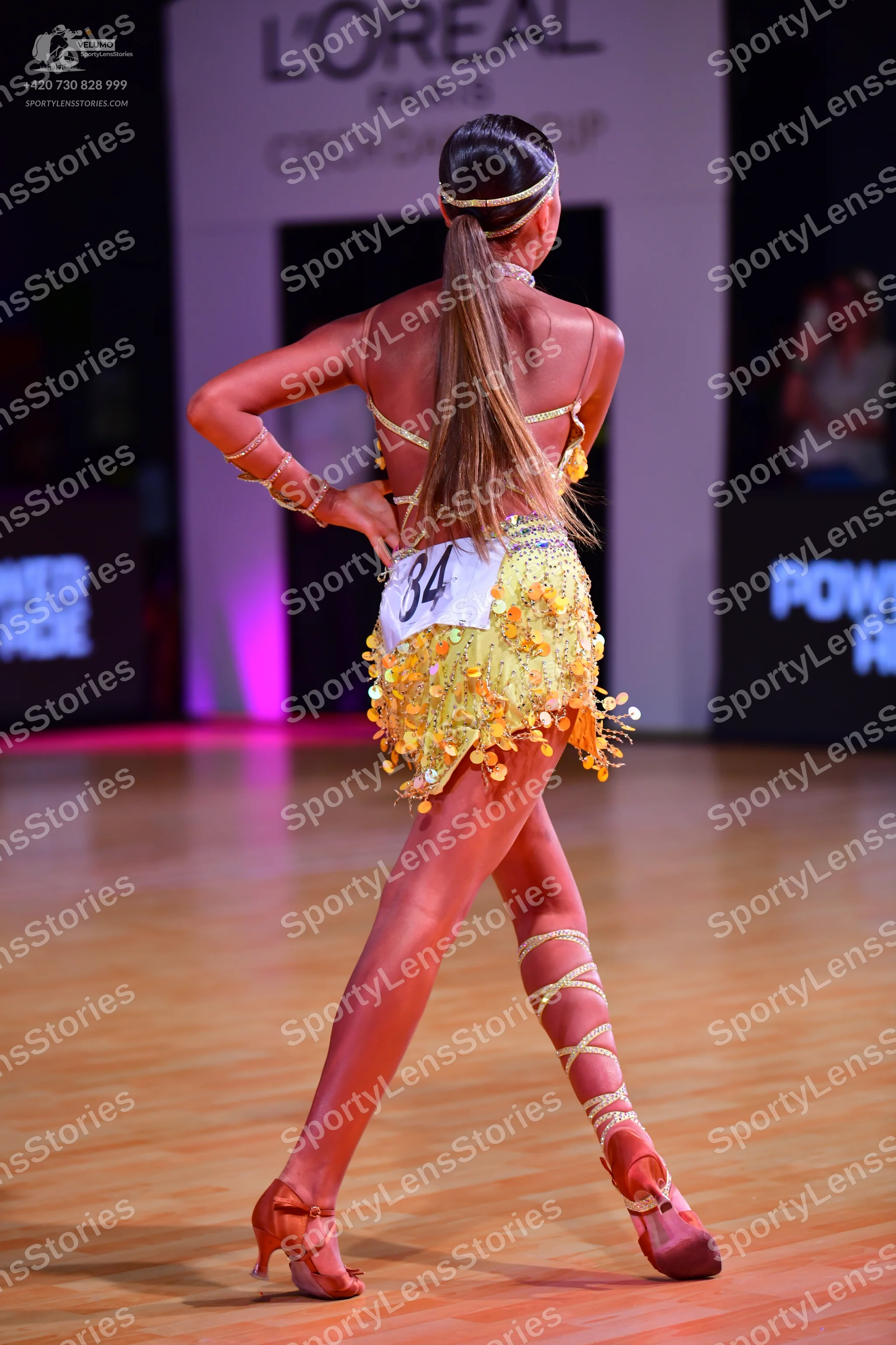 Dancesport competitor: Female dancer: yellow/gold Latin dance dress with sequins and fringe, featuring