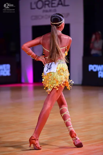 Dancesport competitor: Female dancer: yellow/gold Latin dance dress with sequins and fringe, featuring 