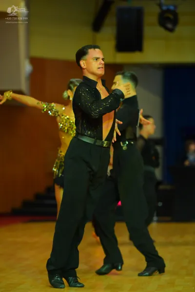 Dancesport competitor: Male dancer in foreground: black long-sleeved shirt with sequins, black trousers