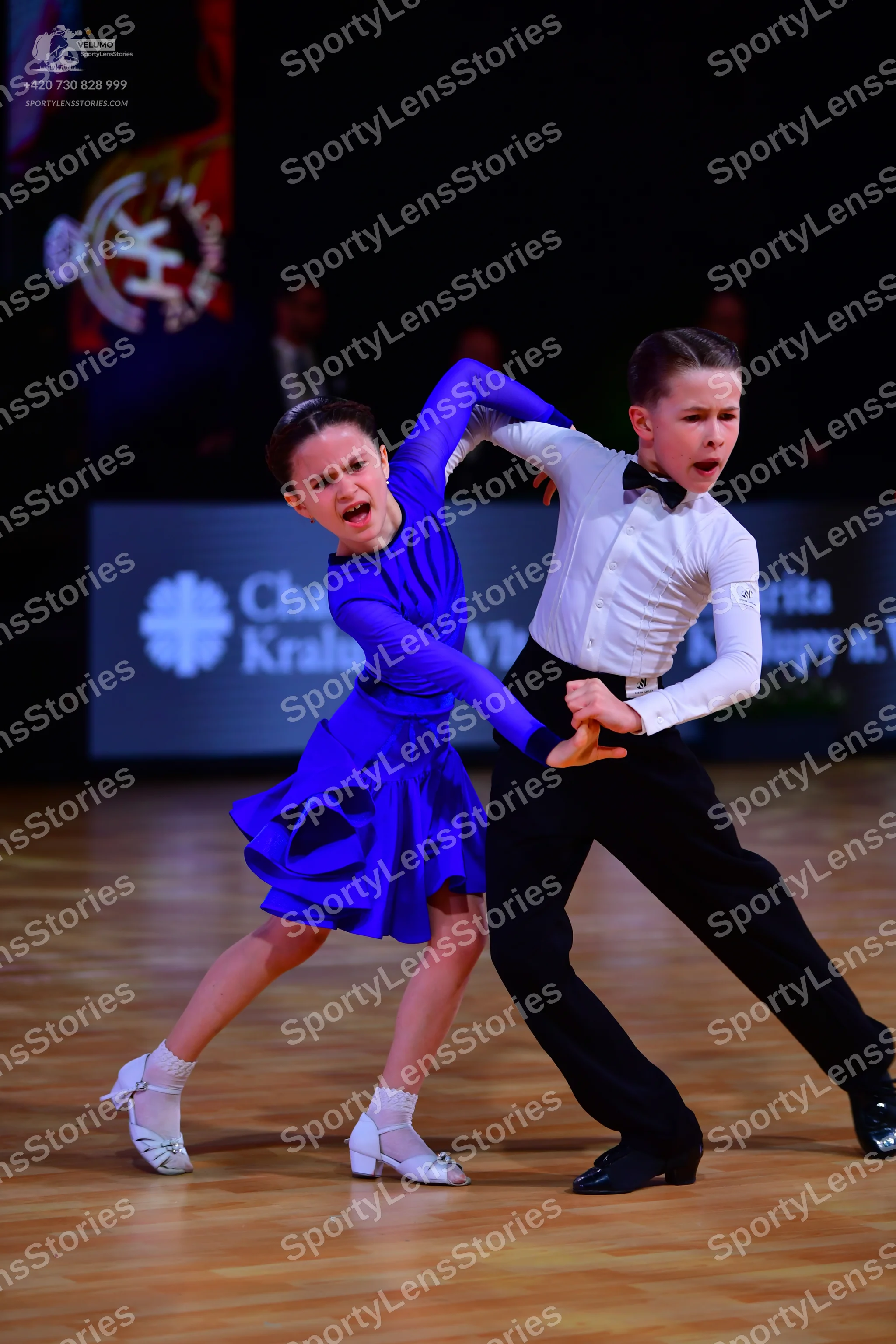 Dancesport competitor: Female dancer: bright blue long-sleeved Latin dress with a short flared skirt, w
