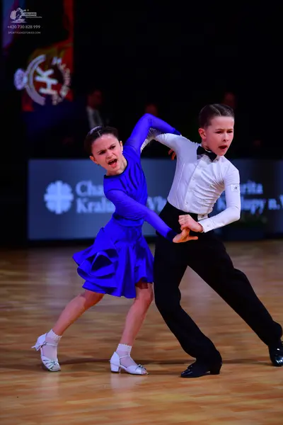 Dancesport competitor: Female dancer: bright blue long-sleeved Latin dress with a short flared skirt, w
