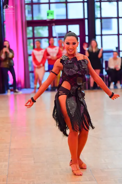 Dancesport competitor: Female dancer: black Latin dress with large 3D fabric floral appliqués on the bo