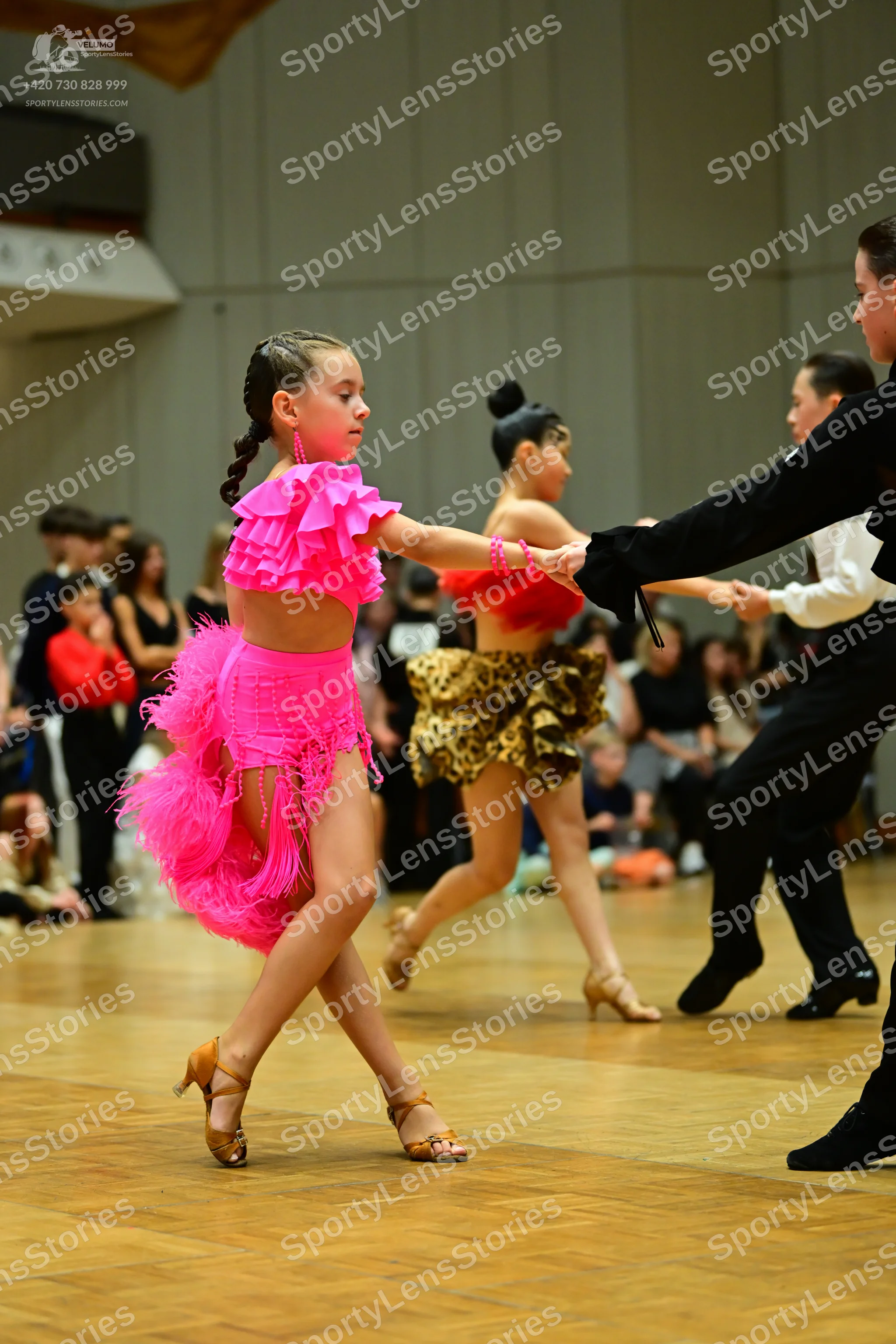 Dancesport competitor: Female dancer 1: bright pink Latin dress with ruffled sleeves and a fringe skirt