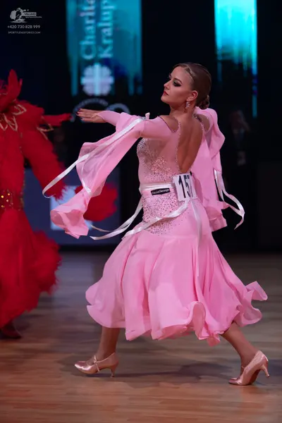 Dancesport competitor: Female dancer in pink: light pink ballroom dress with a sequined bodice, a low o