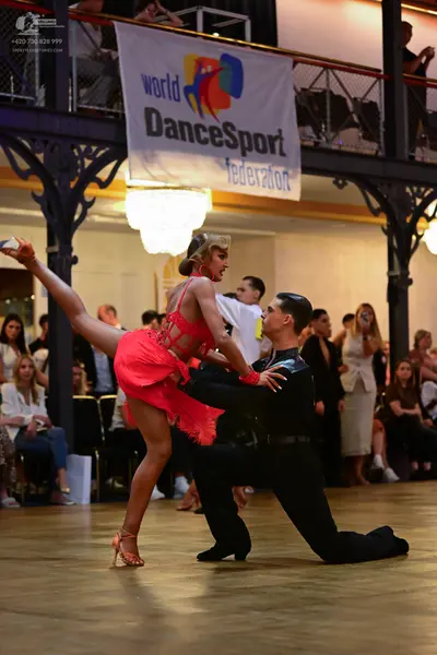 Dancesport competitor: Female dancer: red latin dress with sequins and fringe, nude dance heels