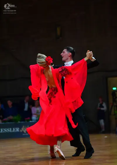 Dancesport competitor: Female dancer: red latin dress with large, flowing ruffled sleeves and red flora