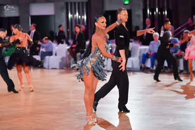 Dancesport competitor: Female dancer (center): grey-blue latin dress with fringe and sequins, large hoo
