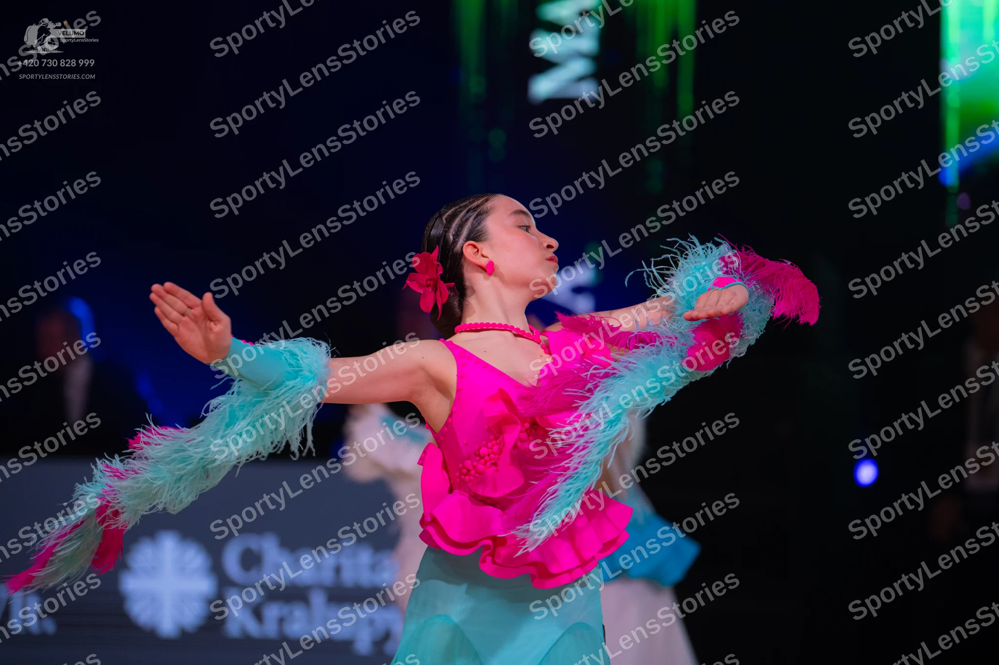 Dancesport competitor: Female dancer: bright pink latin dress with teal/light blue fringe or feather-li