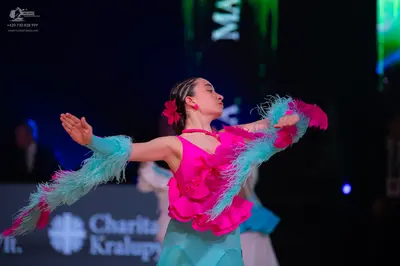 Dancesport competitor: Female dancer: bright pink latin dress with teal/light blue fringe or feather-li