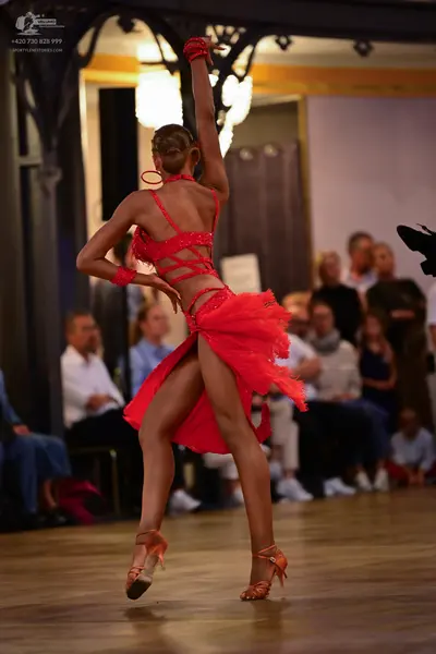 Dancesport competitor: Female dancer: red latin dress with a strappy back and red wristbands