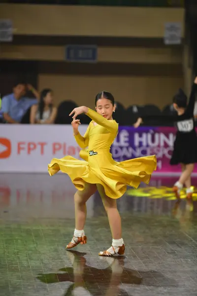 Dancesport competitor: Female dancer: bright yellow, long-sleeved ballroom dress with a voluminous, flo
