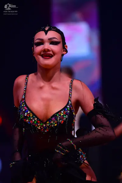 Dancesport competitor: Female dancer: black latin dress with multi-colored rhinestones and fringe, pair