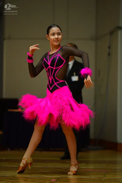 Dancesport competitor: Female dancer: hot pink and black Latin dress with long sheer black sleeves, pin