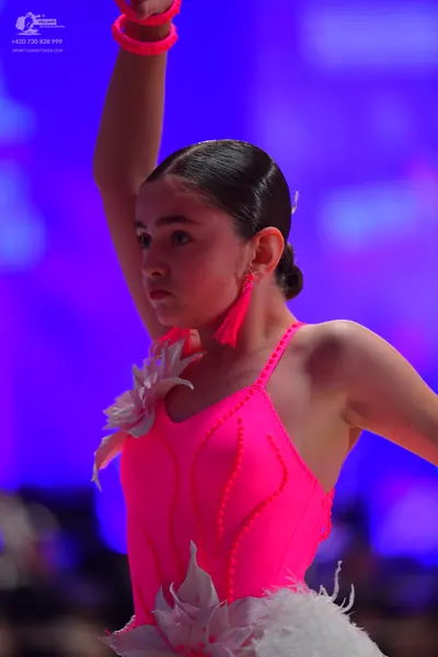 Dancesport competitor: Female dancer: neon pink Latin dress with white feathery/ruffled embellishments 