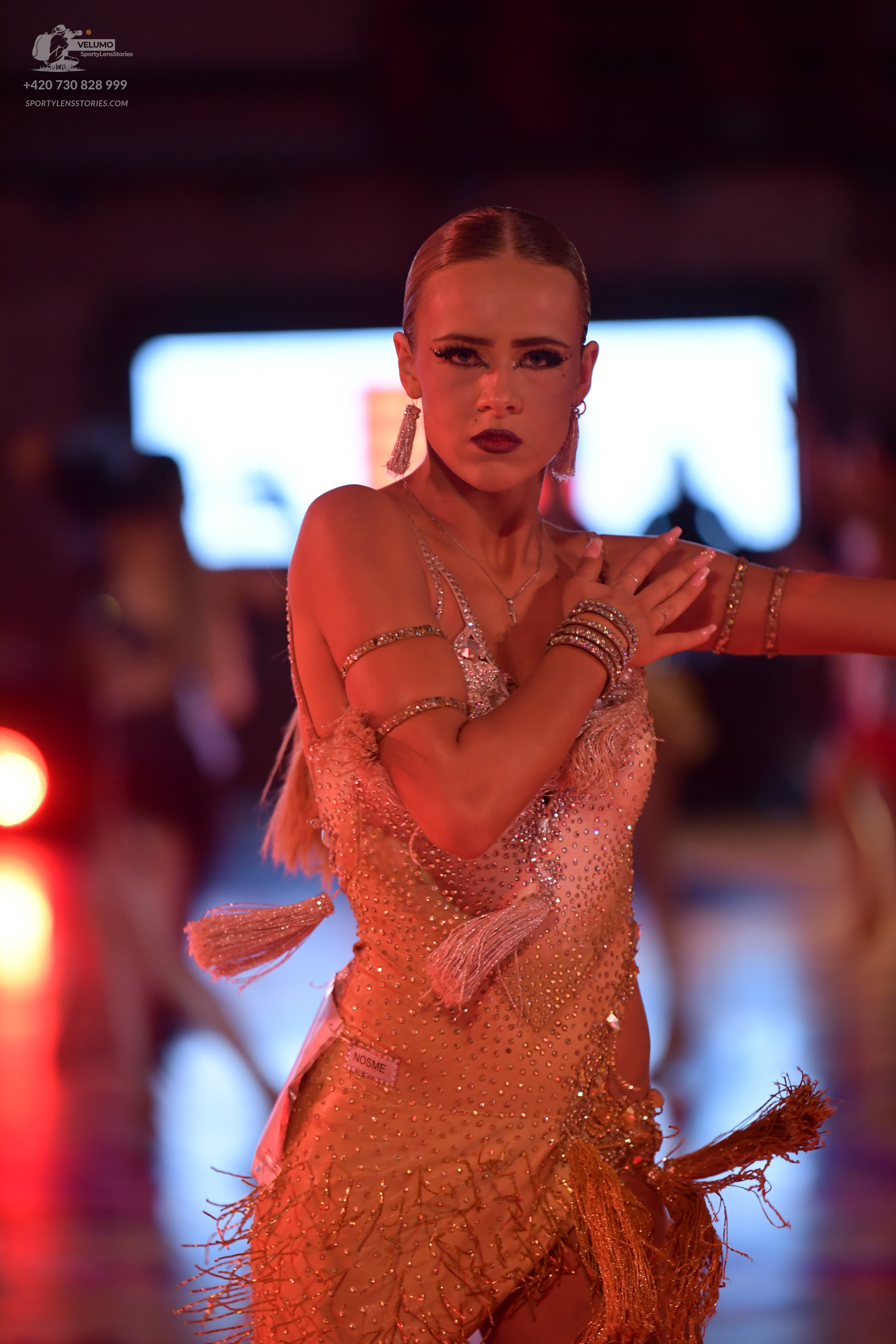 Dancesport competitor: Female dancer: gold/champagne-colored Latin dress featuring sequins and long fri