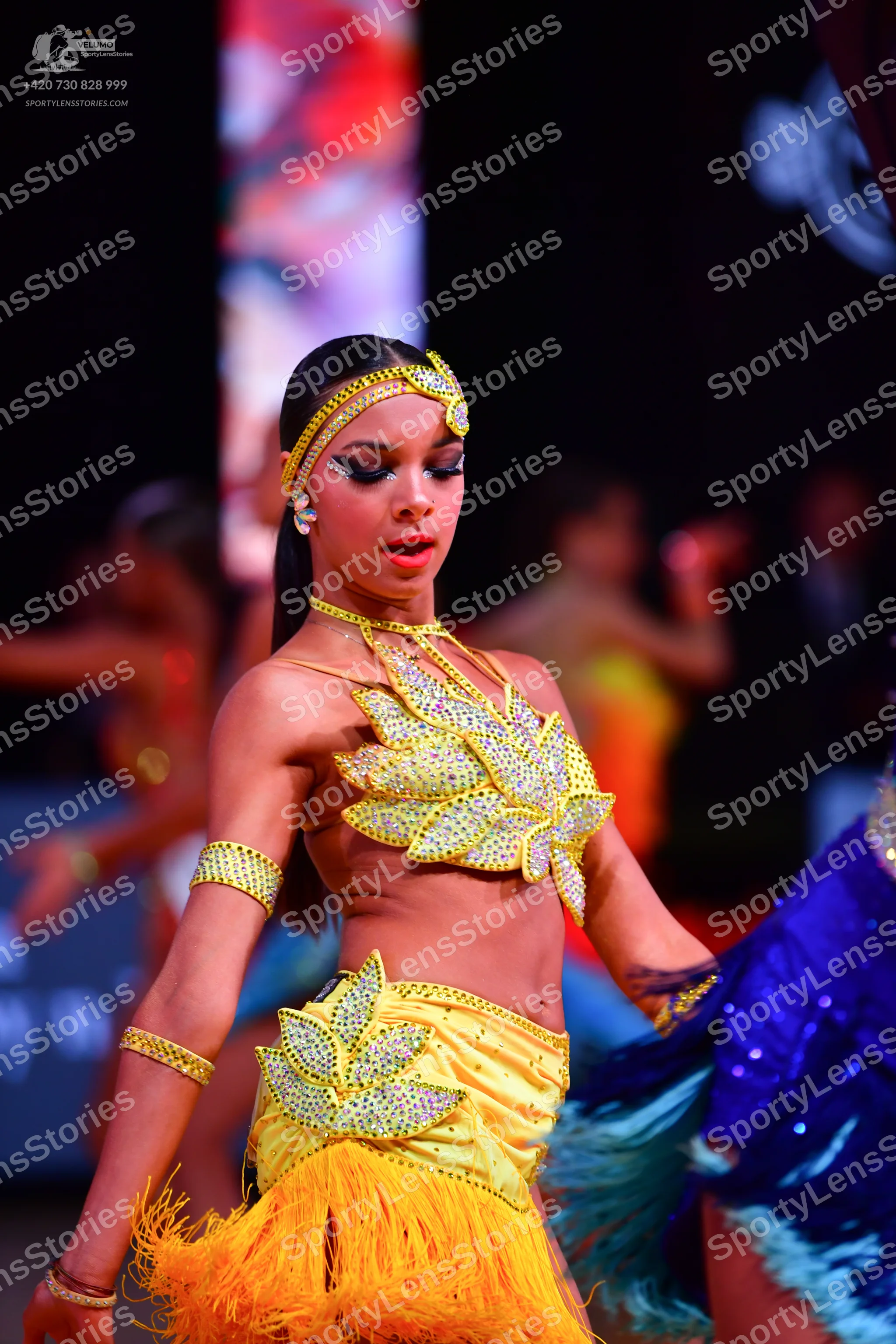 Dancesport competitor: Female dancer in foreground: yellow two-piece Latin dress with silver sequin lea