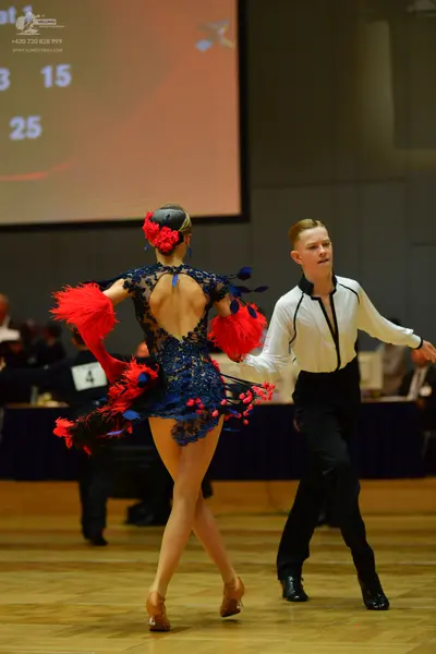 Dancesport competitor: Female dancer: navy blue lace Latin dress with red and bright blue feathery/frin