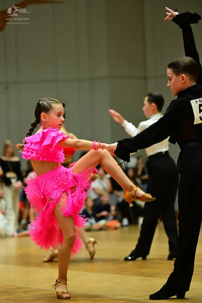 Dancesport competitor: Female dancer: bright pink latin dress with heavy fringe and matching pink wrist