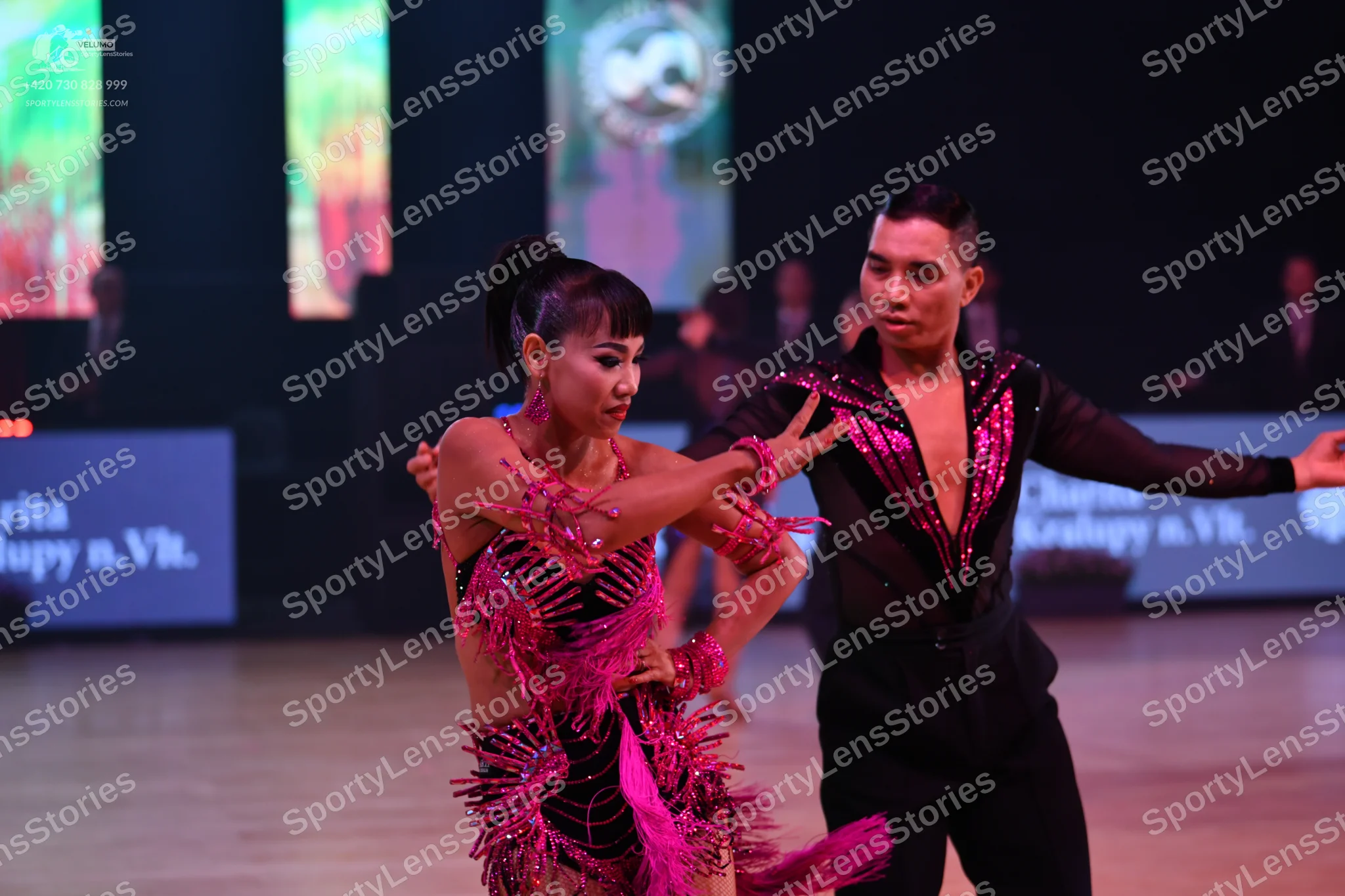 Dancesport competitor: Female dancer: pink and black latin dress with fringe and sequins