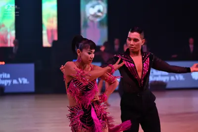 Dancesport competitor: Female dancer: pink and black latin dress with fringe and sequins