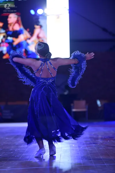 Dancesport competitor: Female dancer: blue Latin dance dress with sequin embellishments and feather tri
