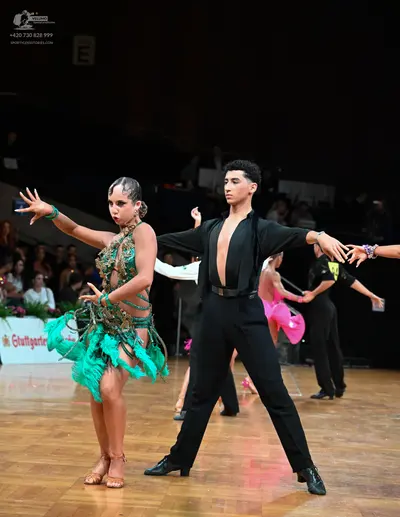 Dancesport competitor: Female dancer in foreground: emerald green Latin dance dress with an embellished