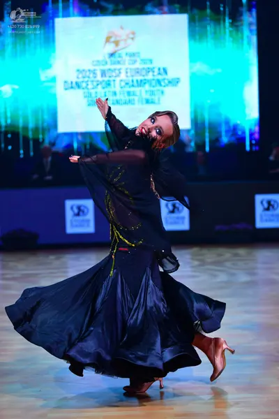 Dancesport competitor: Female dancer: dark blue ballroom dress with a sheer top featuring gold/yellow s