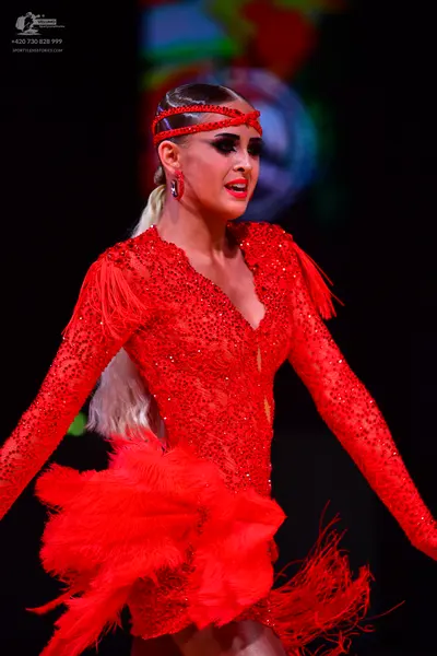 Dancesport competitor: Female dancer: red latin dress with sequins and fringe, red headband, and red ea