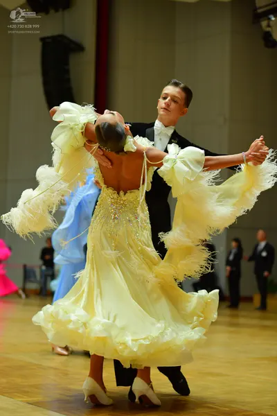 Dancesport competitor: Female dancer: light yellow Latin dress with a sequined bodice and large, ruffle