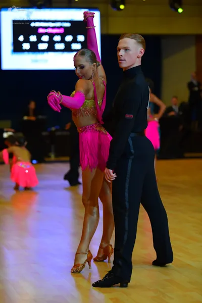 Dancesport competitor: Female dancer: bright pink Latin dance costume with gold/yellow sequin embellish