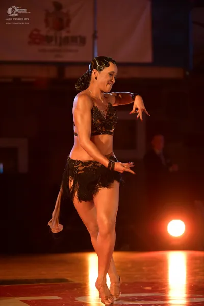 Dancesport competitor: Female dancer: black lace/mesh Latin costume with a bra top and a skirt featurin