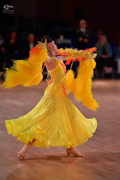 Dancesport competitor: Female dancer: bright yellow ballroom dress with large, voluminous yellow feathe