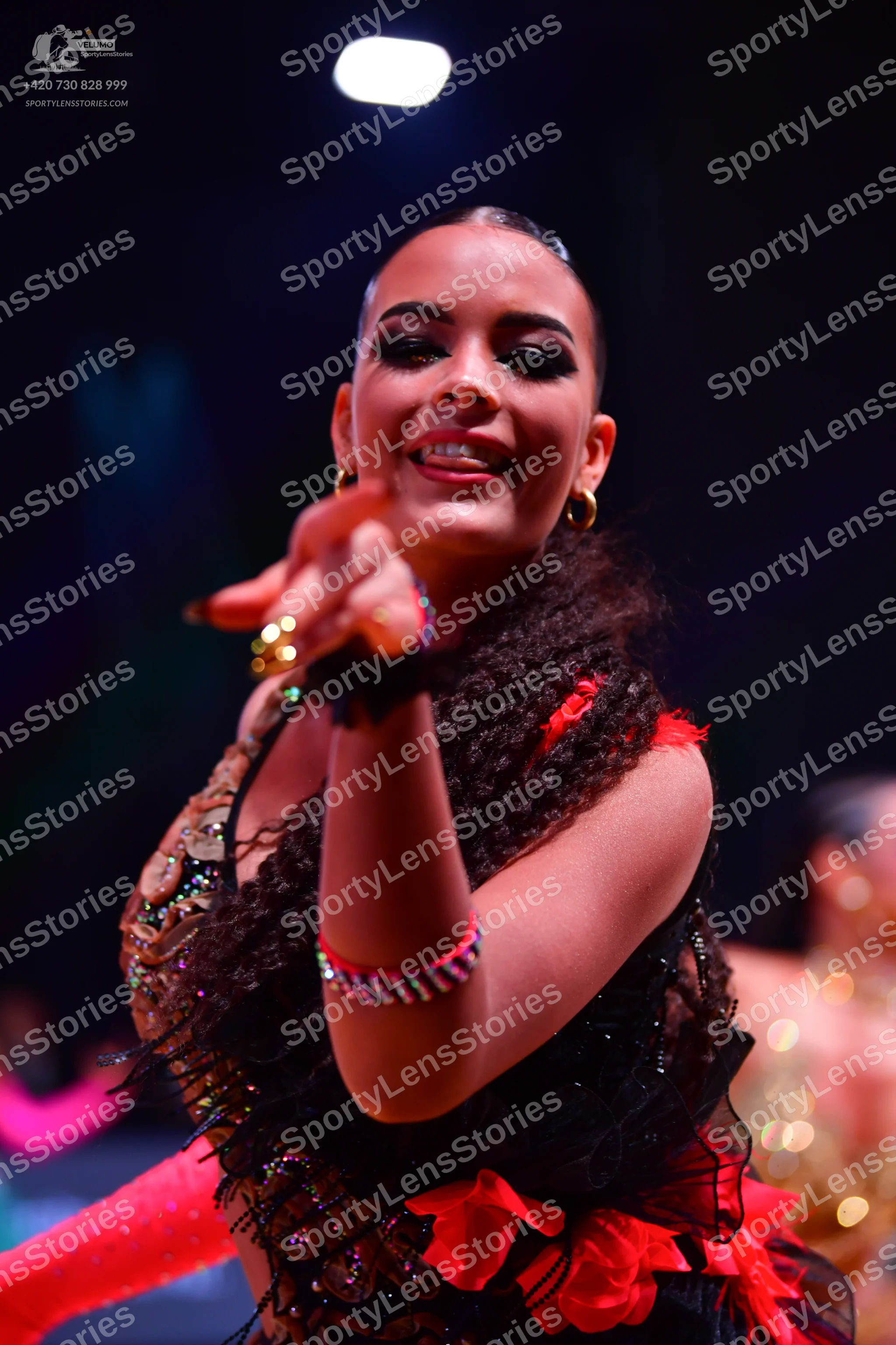 Dancesport competitor: Female dancer: black Latin dress with sequins and red fabric accents