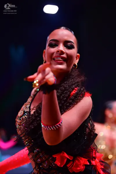 Dancesport competitor: Female dancer: black Latin dress with sequins and red fabric accents