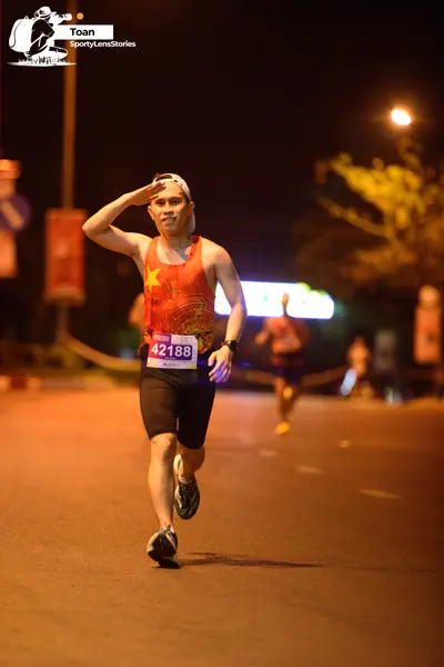 Marathon runner #42188: Runner 1: red/orange tank top, black shorts, black shoes, white headband