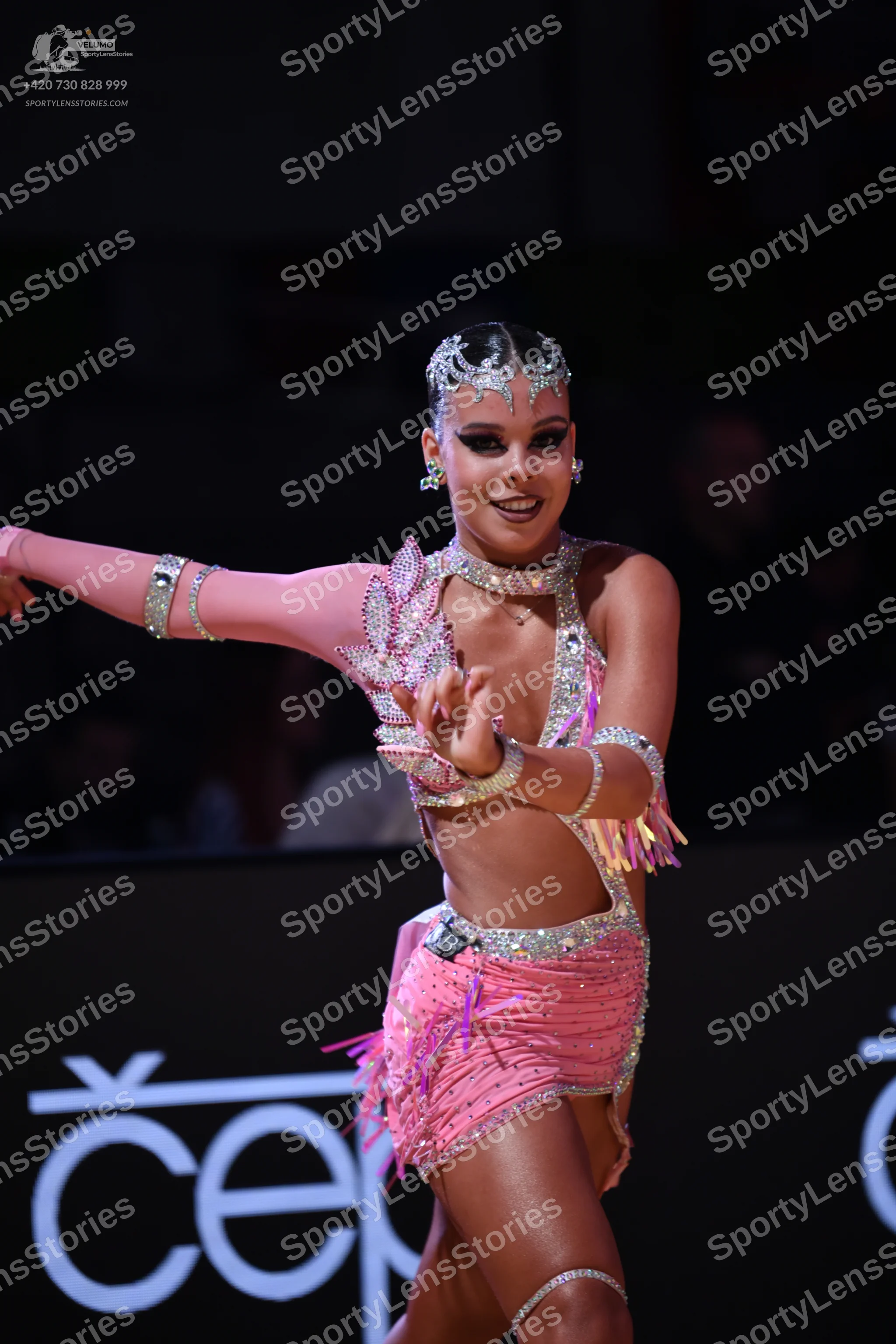 Dancesport competitor: Female dancer: pink latin dance costume with sequins and fringe, including a mat